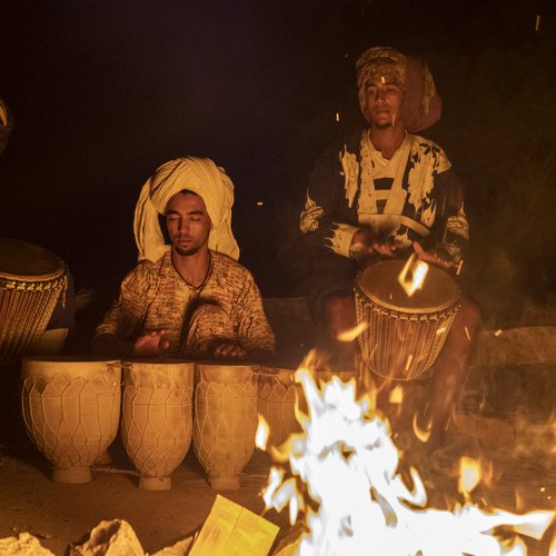 Two Arab musicians play their instruments at night